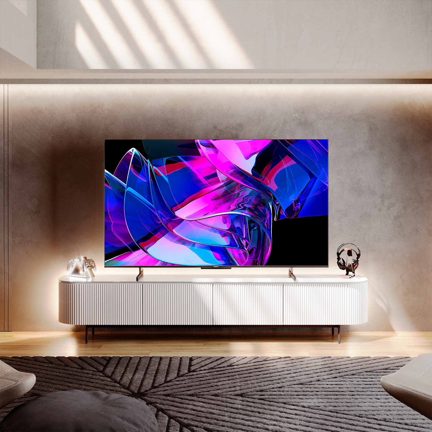 Un televisor muestra un diseño abstracto. Está sobre un mueble blanco. Una luz brilla desde arriba.