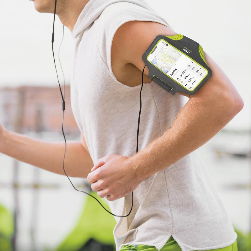 Ein Mann läuft mit einem Telefon in einer Armbinde und trägt Ohrhörer.