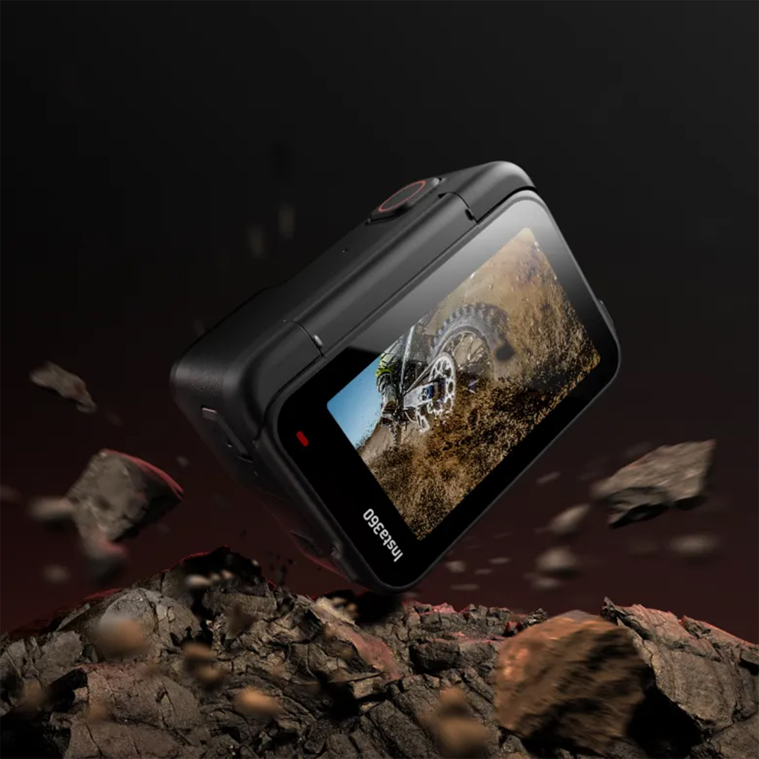 Fotocamera Insta360 nera su una superficie rocciosa, che mostra una scena di motocicletta sullo schermo.