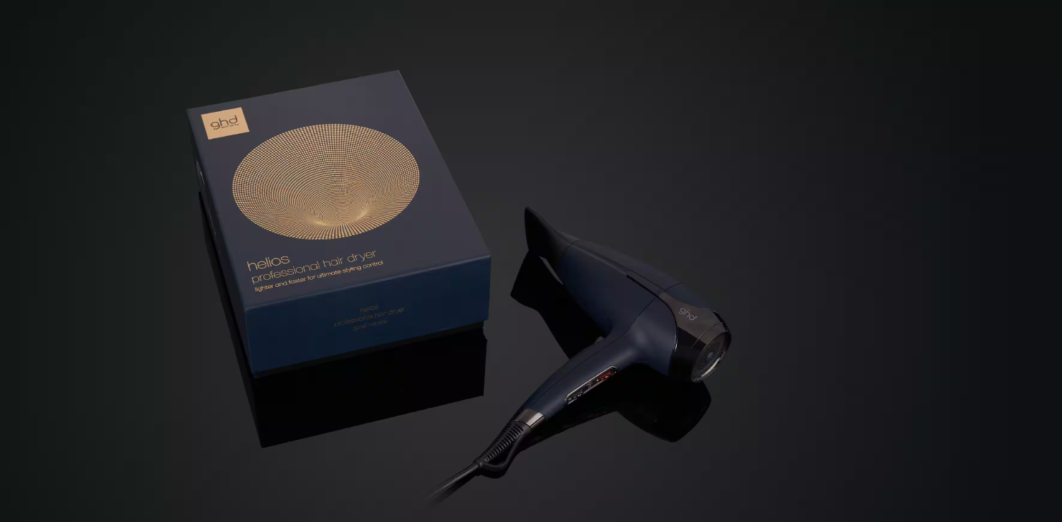 Secador de pelo GHD y caja sobre una superficie oscura, diseño elegante con mango negro.