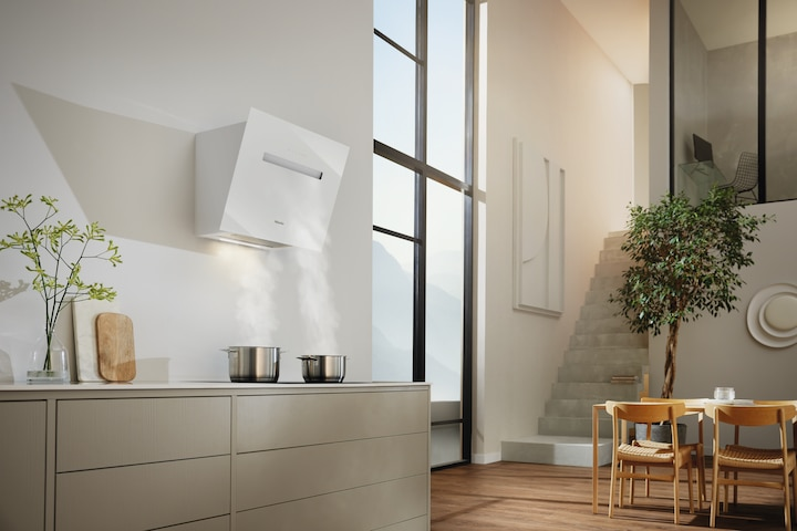 Moderne Küche mit weißer Dunstabzugshaube. Zwei Töpfe auf einem Kochfeld. Helles, sonniges Interieur.
