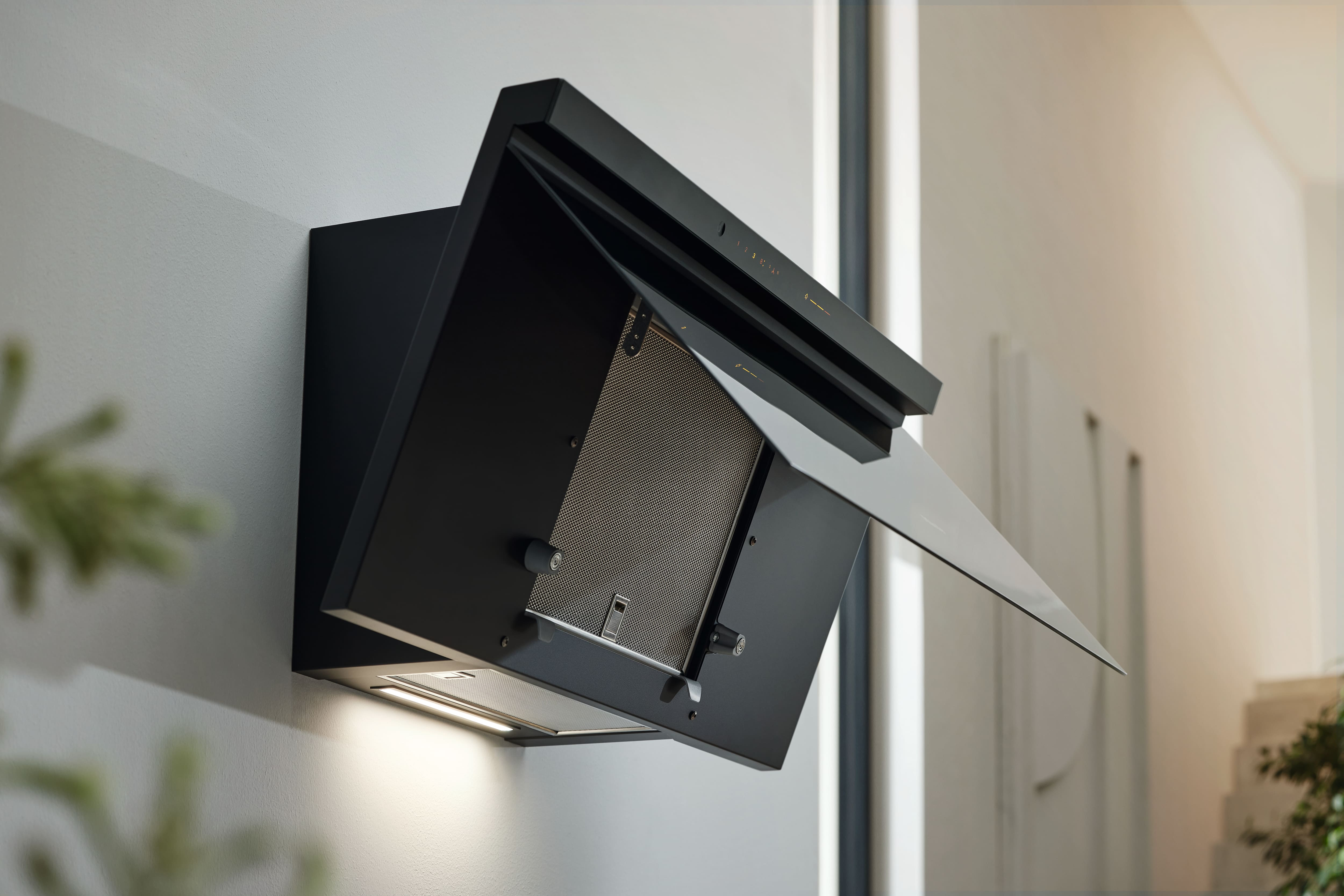 Schwarze Dunstabzugshaube an der Wand montiert. Geöffnet, mit Metallfilter.