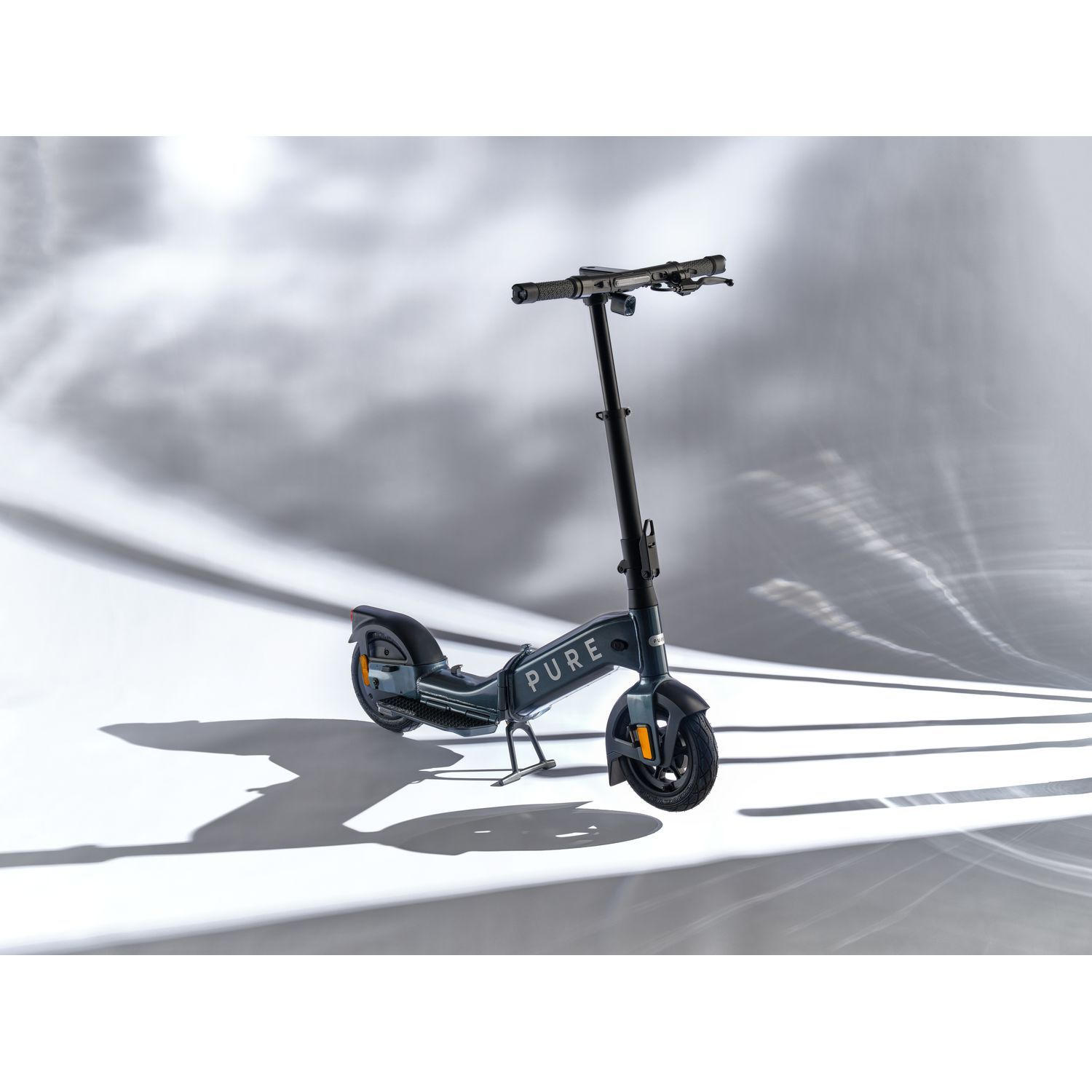 Une trottinette gris foncé sur fond blanc avec effets de lumière.