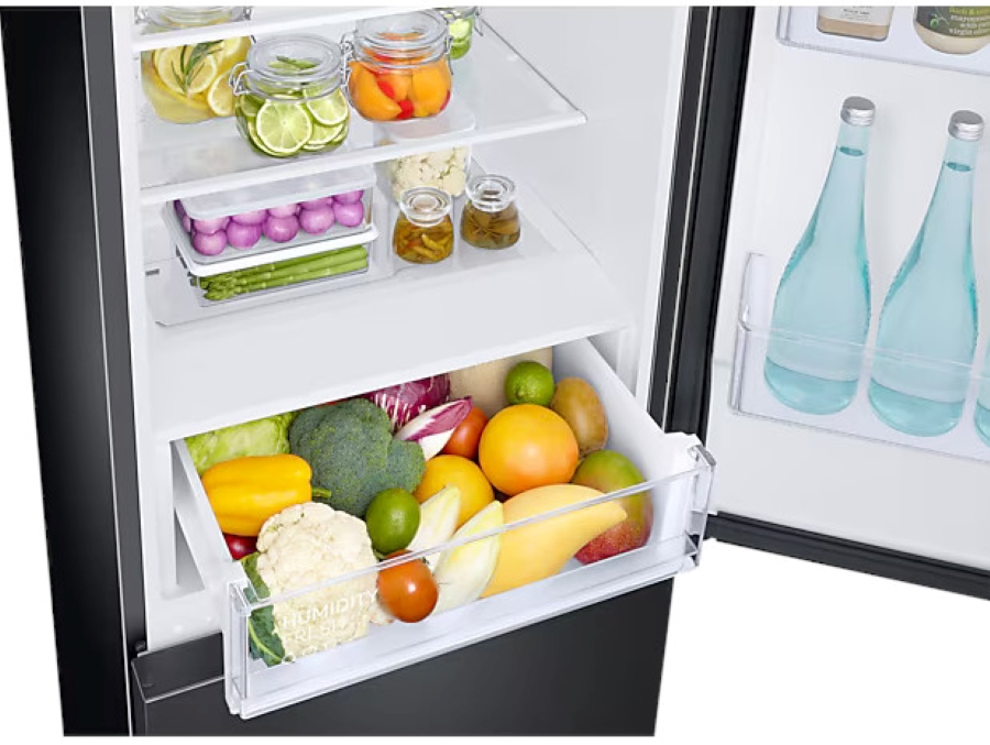 Otwarta lodówka pokazująca szuflady z warzywami i owocami.
