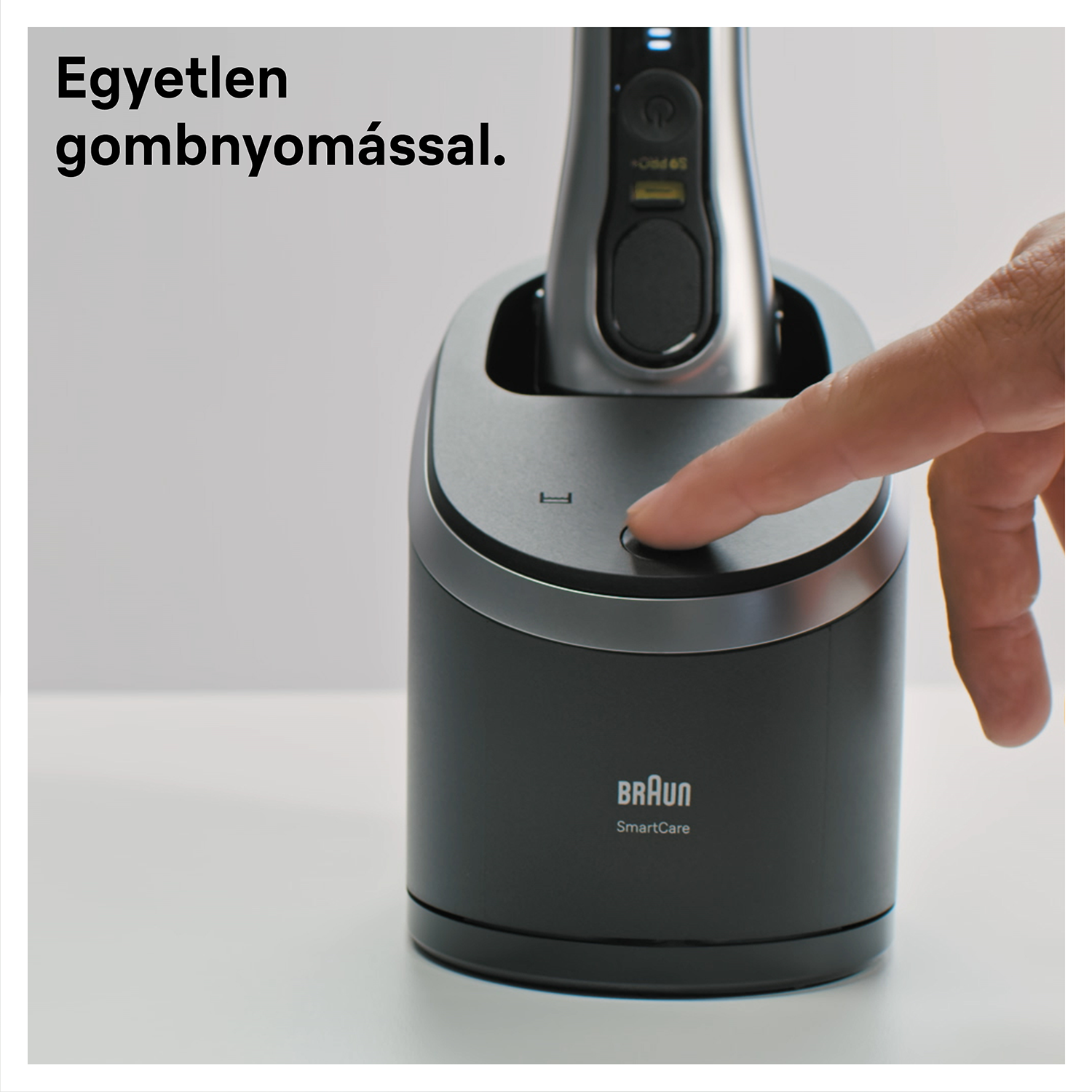 Egy ujj megnyom egy gombot a töltőállomáson, benne egy Braun borotvával.