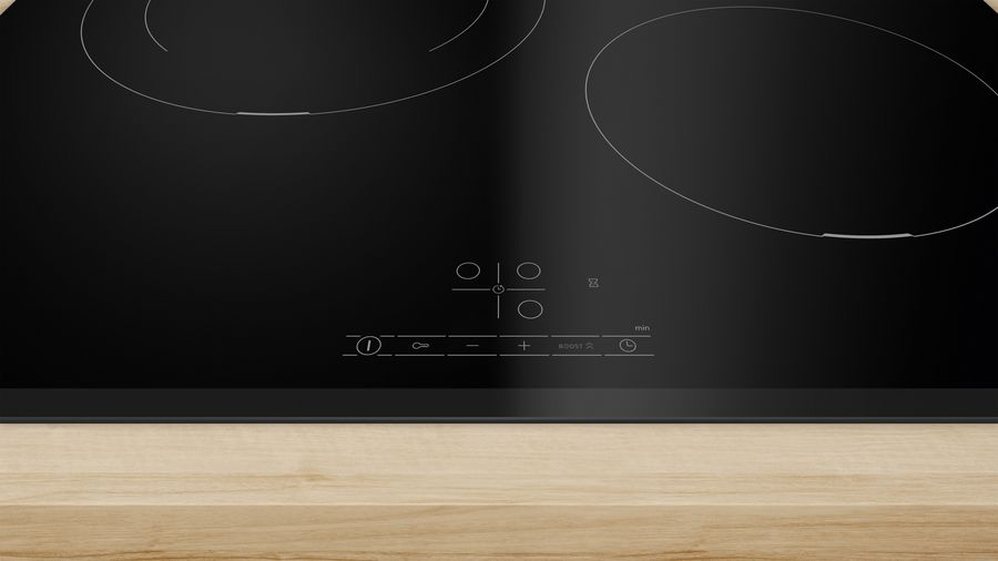 Placa de inducción negra con controles táctiles sobre madera.