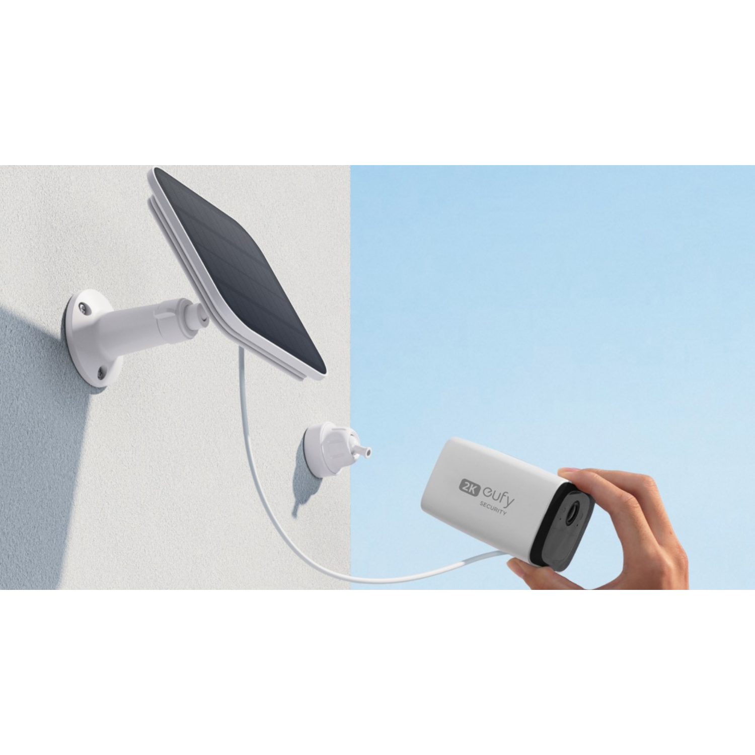 A white wall with a solar panel security camera. The camera is connected to the wall with a cable.