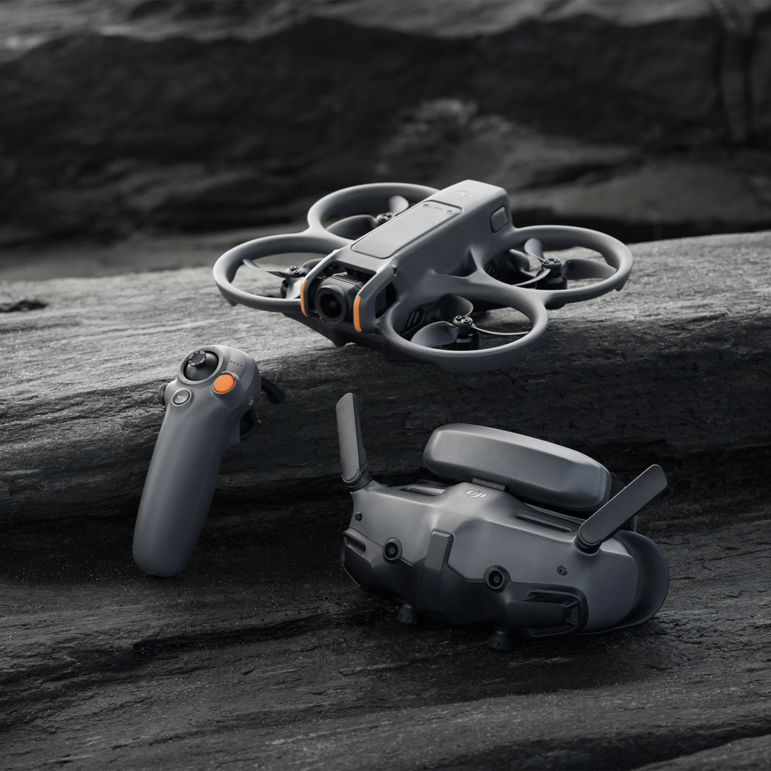 Un drone, un telecomando e degli occhiali sono su una superficie scura e strutturata.