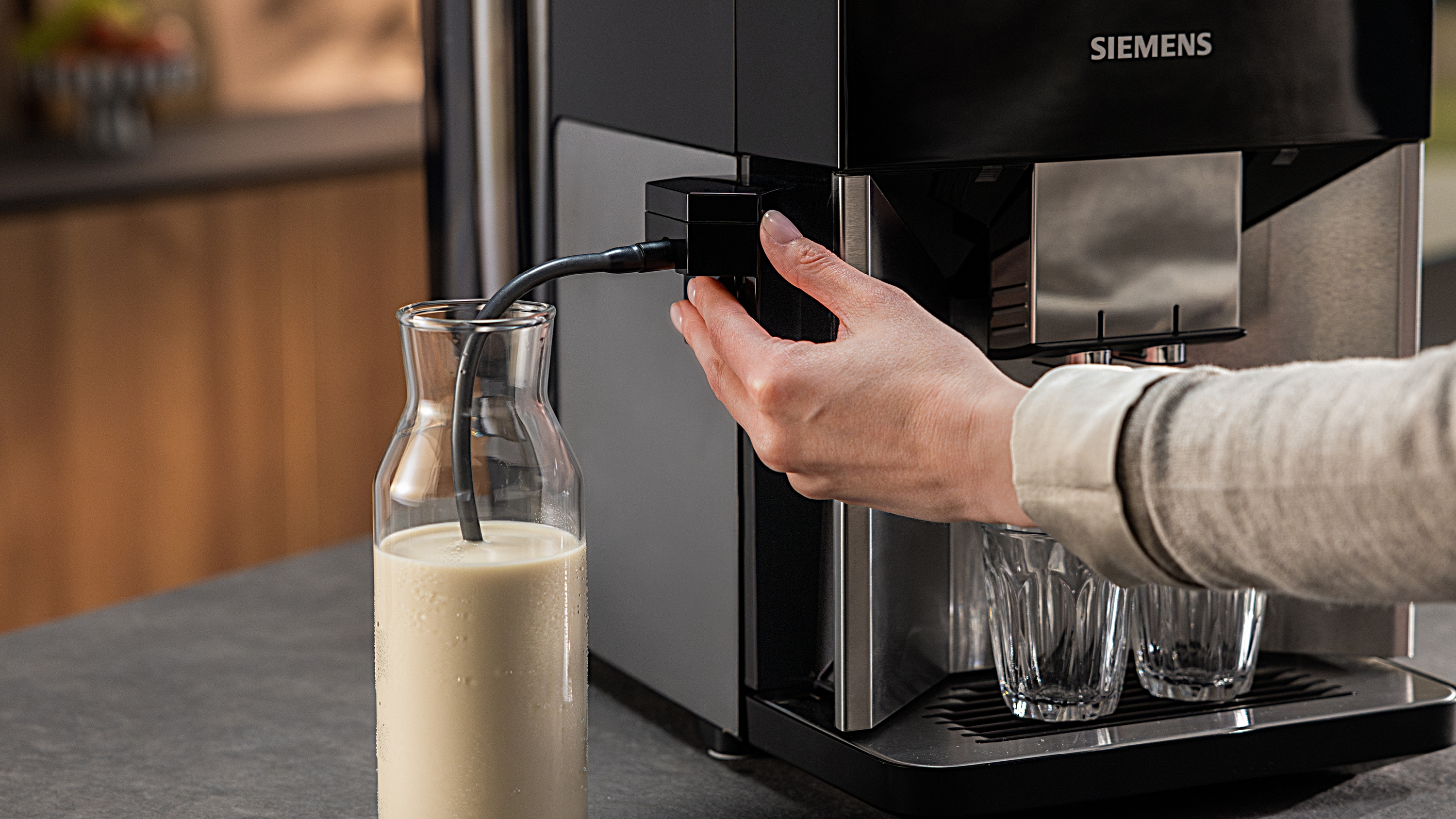 Hand stellt einen schwarzen Schlauch an einer Kaffeemaschine ein.