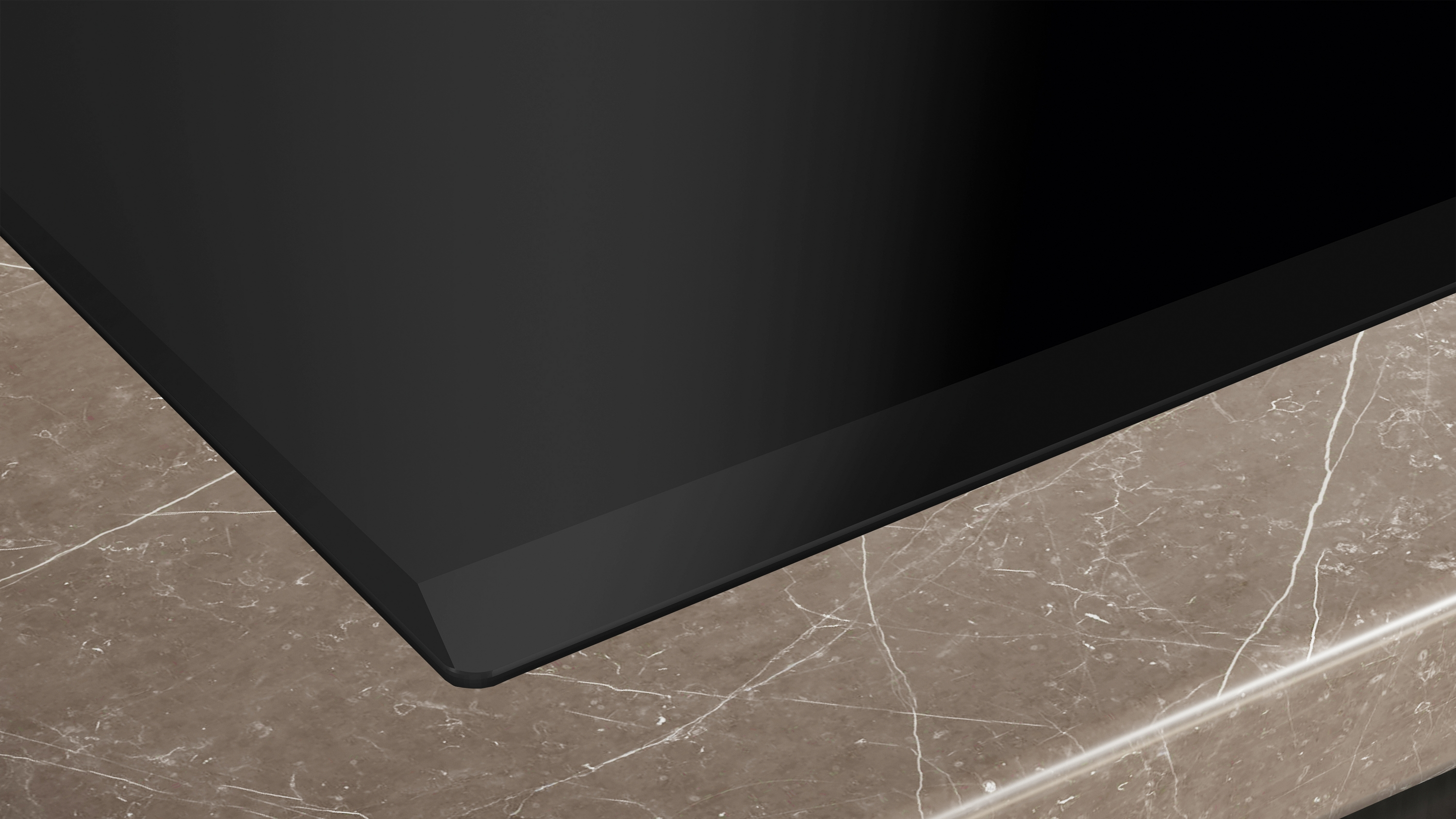 Close-up of a black induction cooktop on a marble countertop. Clean and modern design.