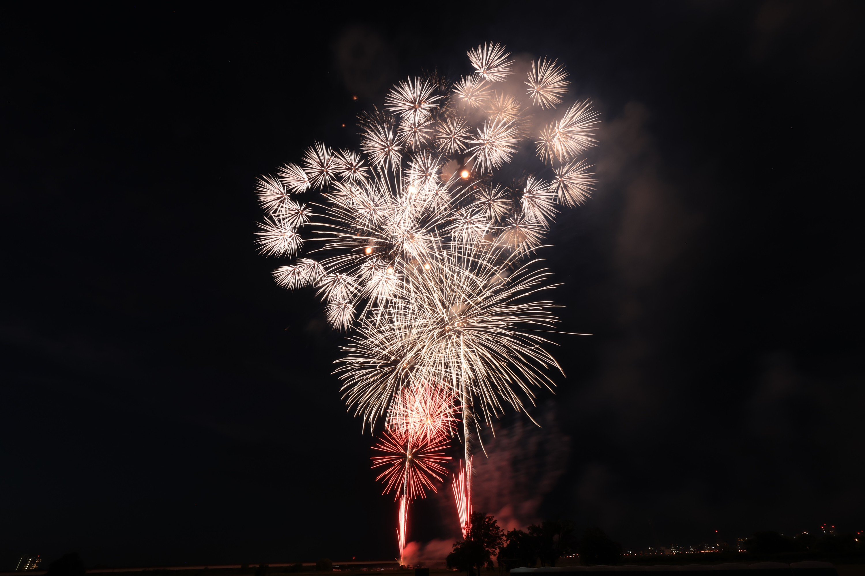 Feuerwerk bei Nacht, mit verschiedenen Lichtblitzen vor dunklem Himmel.