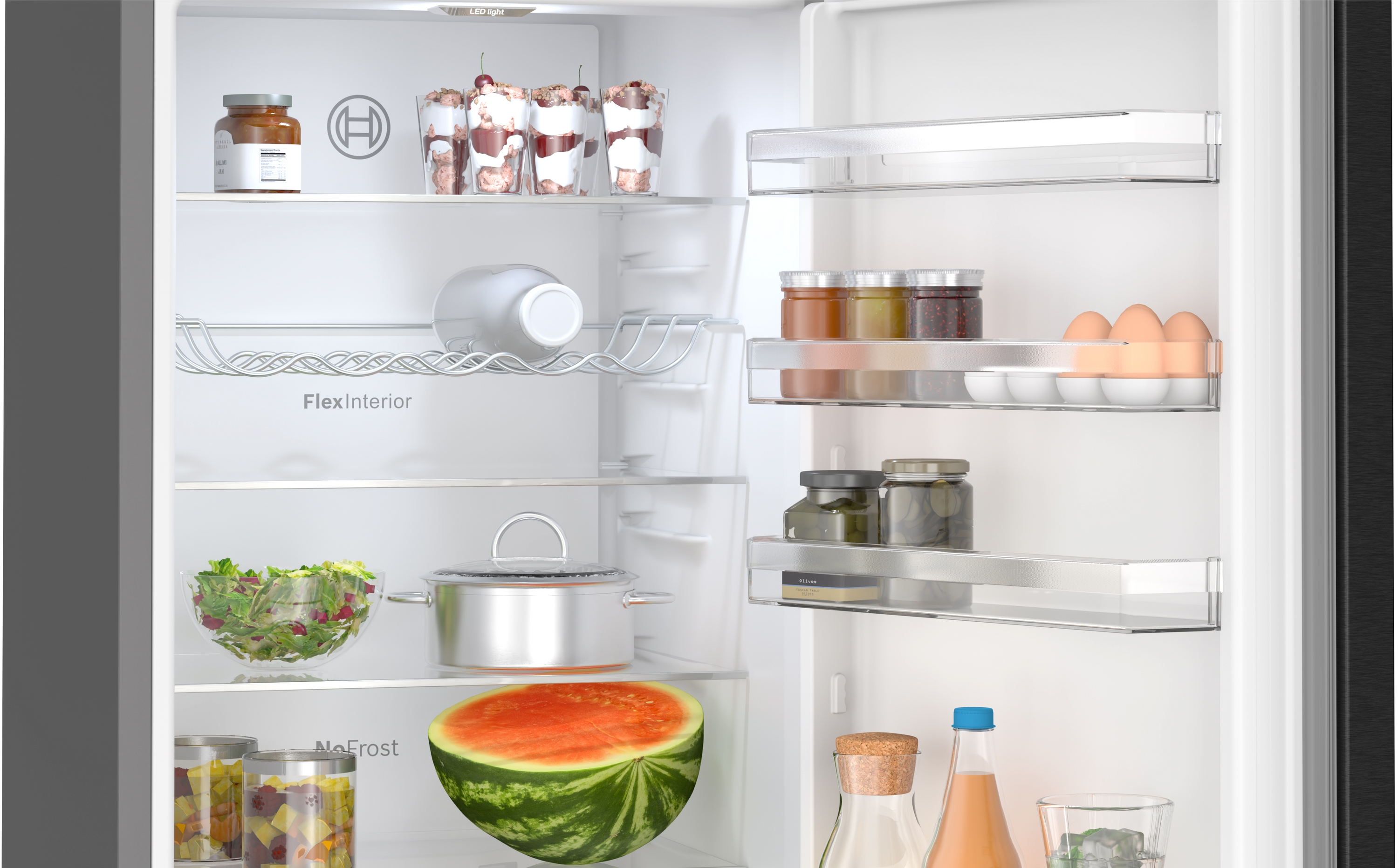 Kühlschrankinnenraum mit Lebensmitteln, darunter Gläser, Wassermelone und Salat.