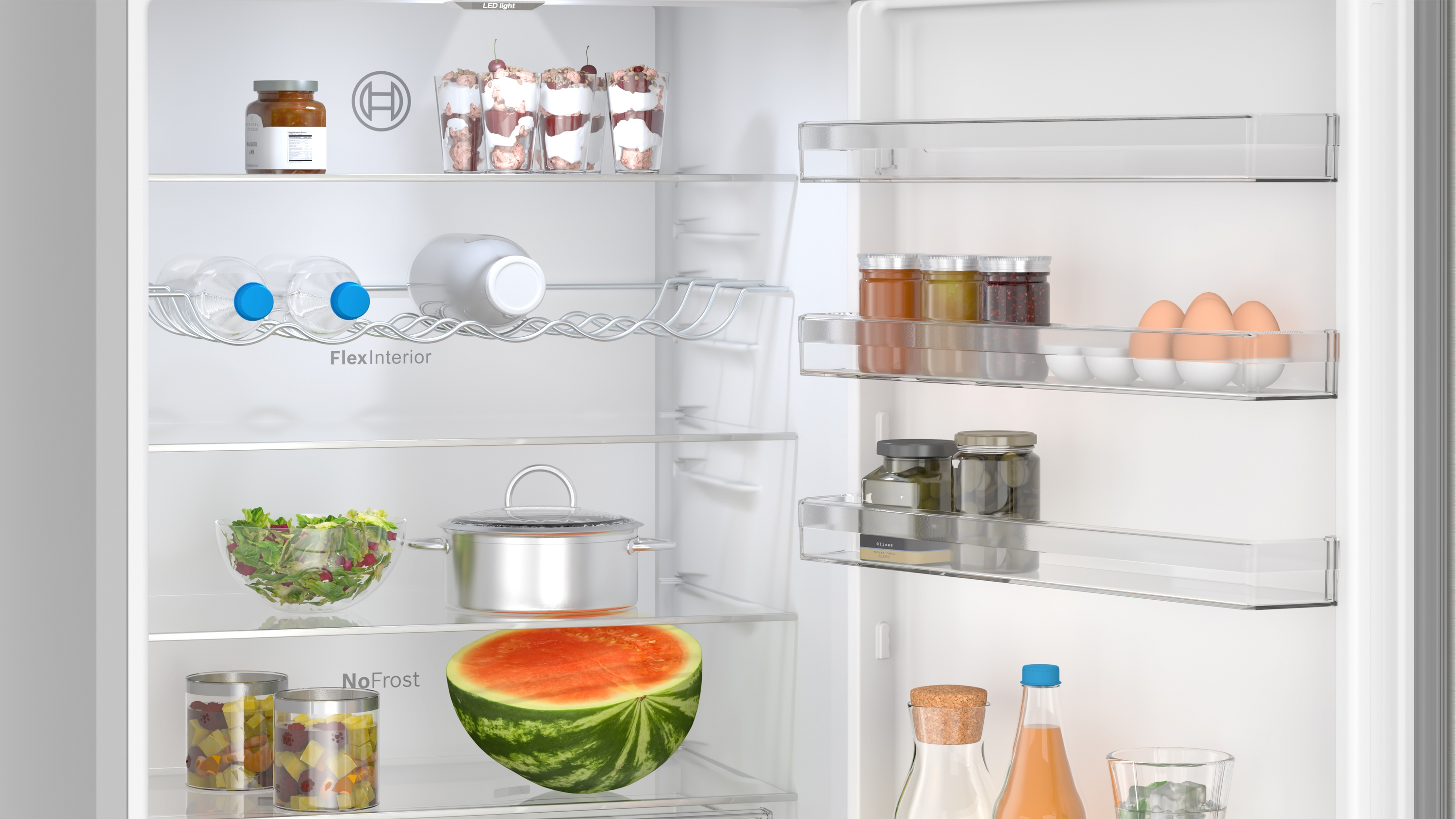 Im Inneren eines Kühlschranks voller Lebensmittel. Gläser, Flaschen, Wasserflaschen und eine Wassermelone. Klare Regale.
