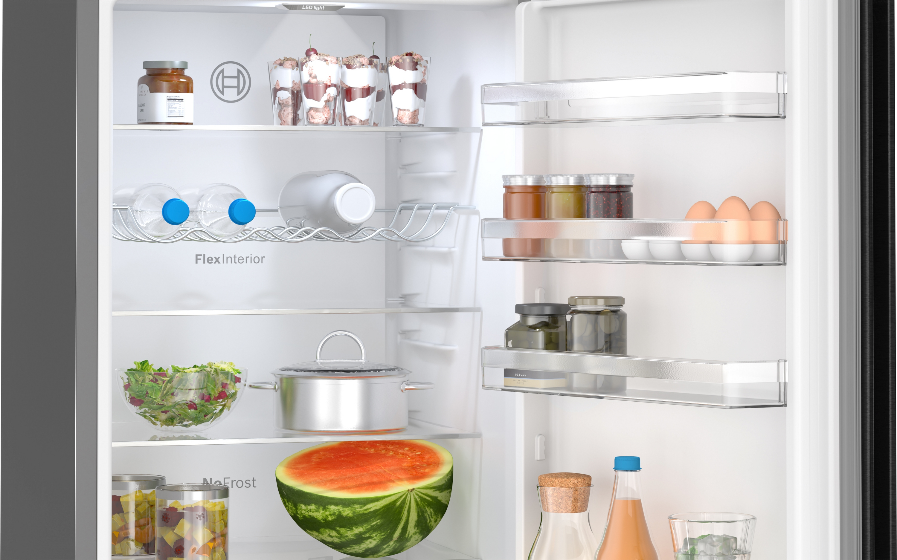 Kühlschrank-Innenraum mit Regalen voller Lebensmittel. Enthält Gläser, Eier und eine Wassermelonen-Hälfte.