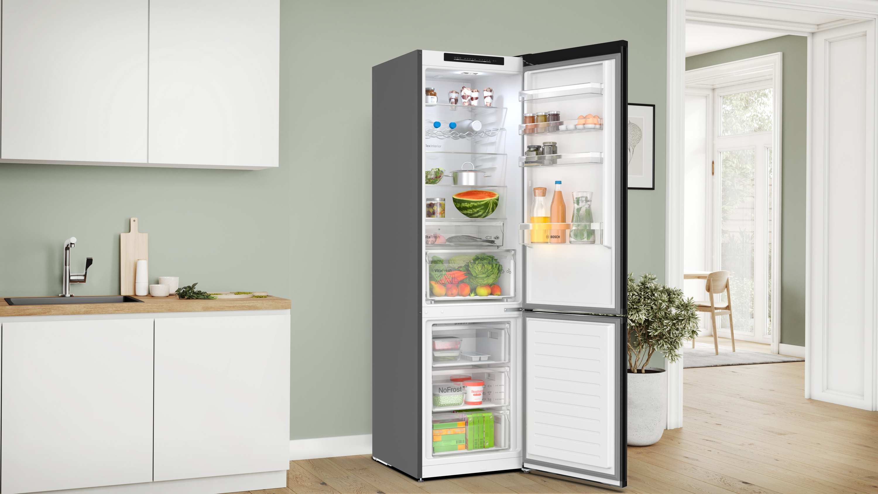 Offener Kühlschrank mit Lebensmitteln. Küchenumgebung mit grünen Wänden.