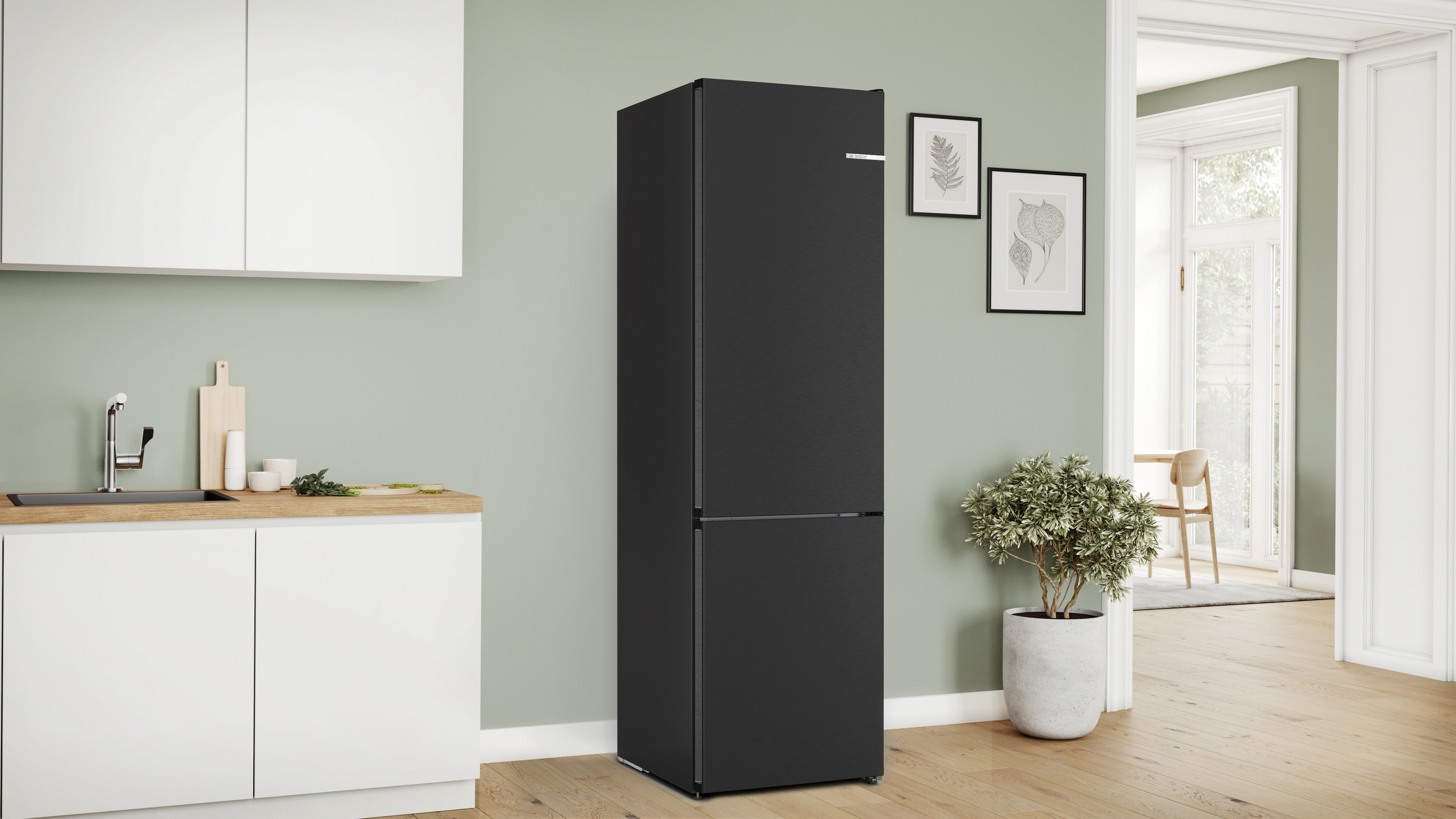 Schwarzer Kühlschrank in einer modernen Küchenumgebung zwischen weißen Schränken und hellgrüner Wand.