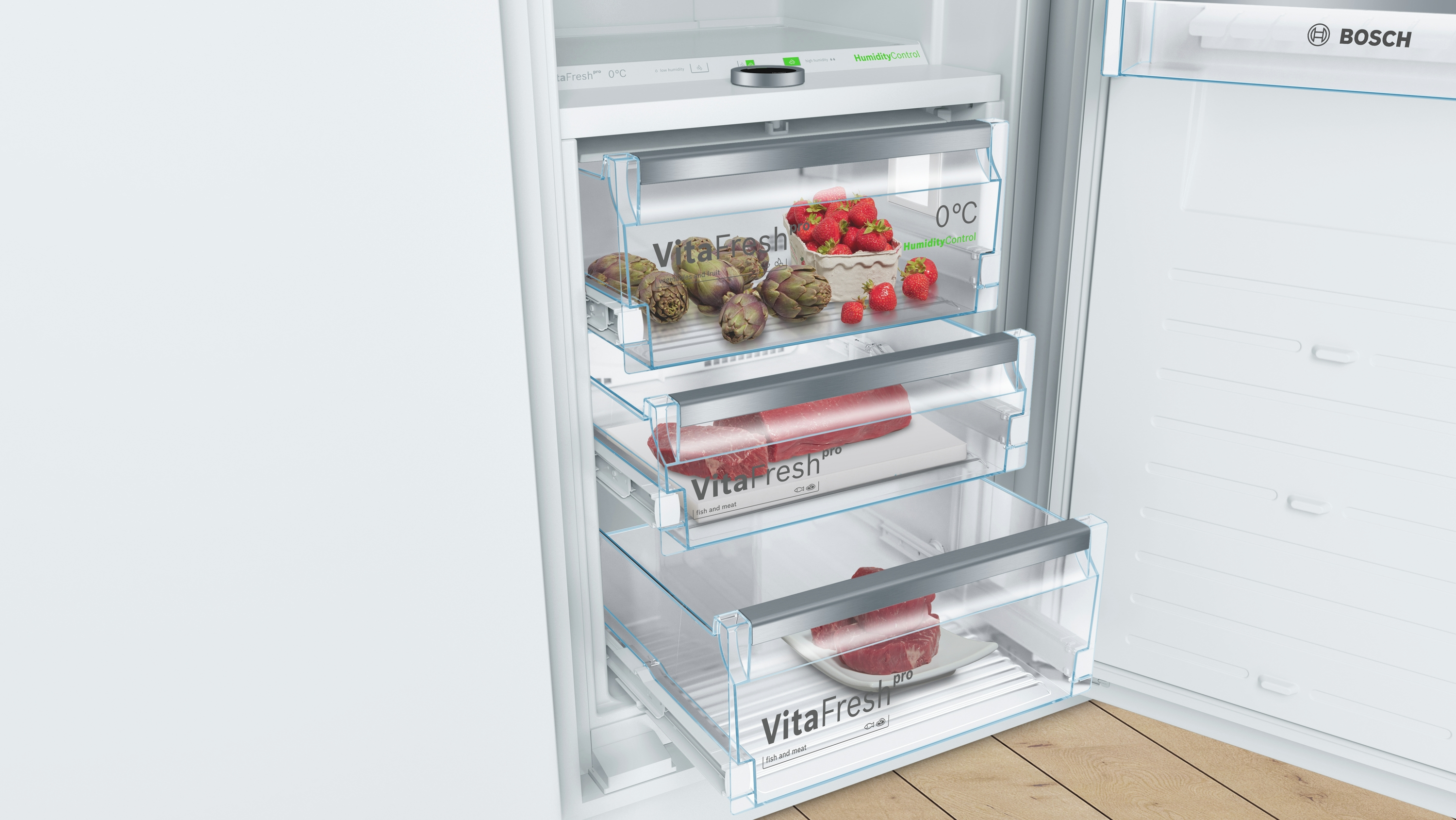 Ein Kühlschrankinnenraum mit drei Schubladen, gefüllt mit Produkten und Fleisch.