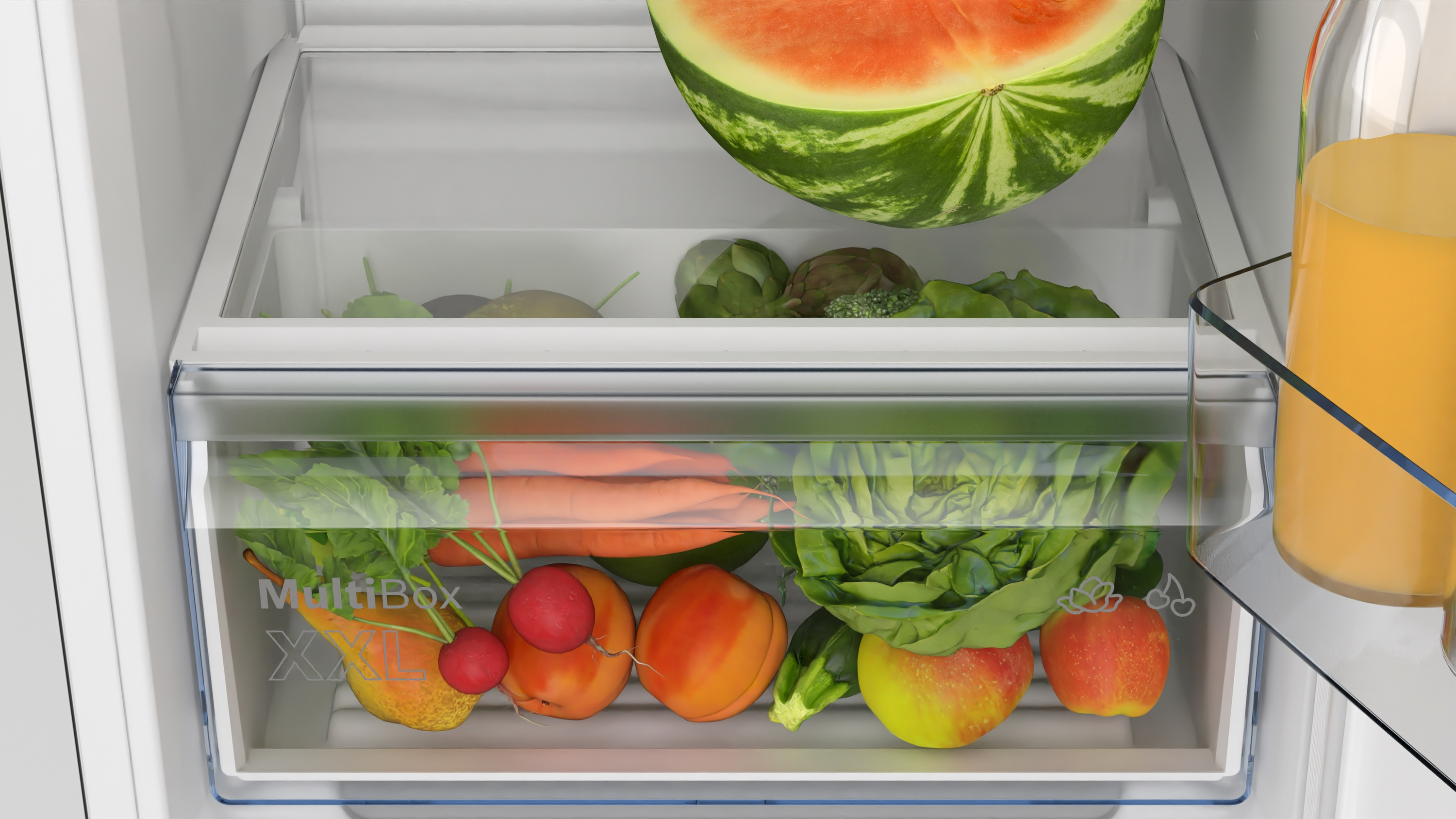 Kühlschublade gefüllt mit Gemüse, Obst und einer Wassermelone.