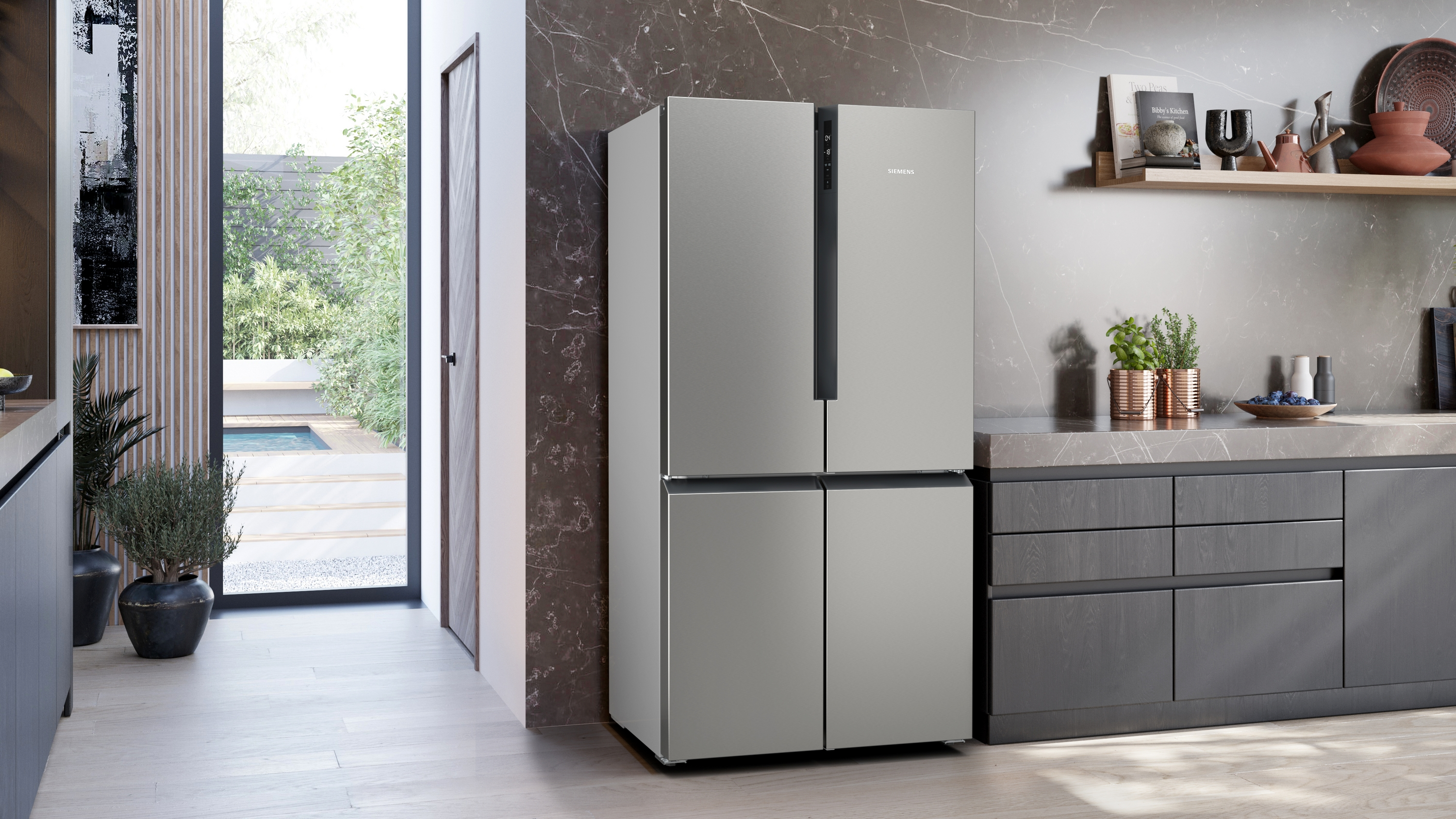 Ein moderner Kühlschrank aus Edelstahl in einer Küche. Er hat vier Türen und steht neben einem Durchgang.
