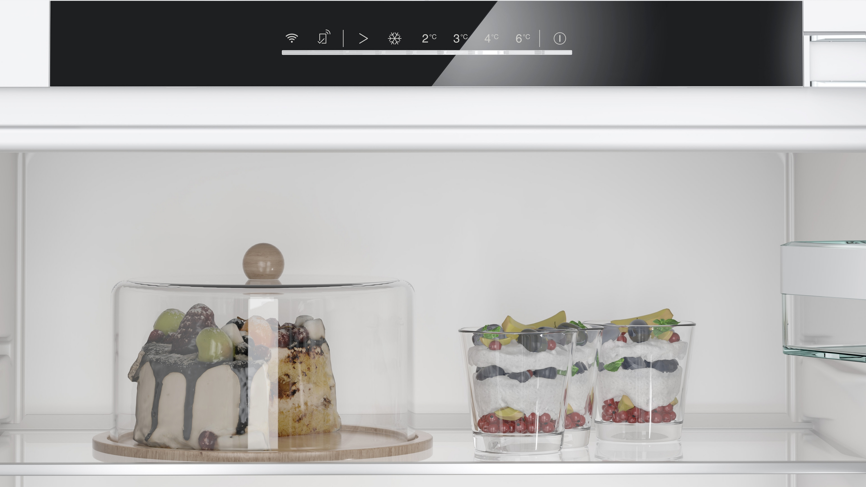 Kühlschrank: Kuchen unter Glas und Desserts in Gläsern, zusammen mit Bedienfeld.
