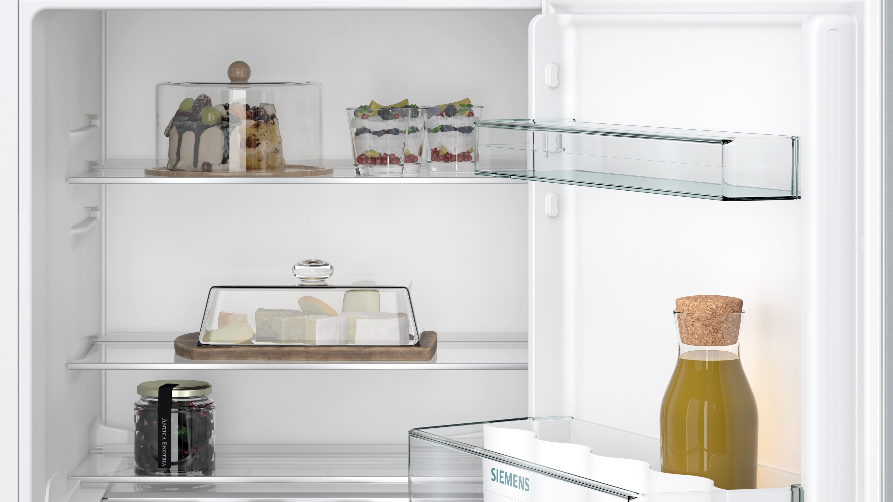 Offener Kühlschrank mit Essen: Kuchen, Käse, Gläser und Flasche. Regale sind sichtbar.