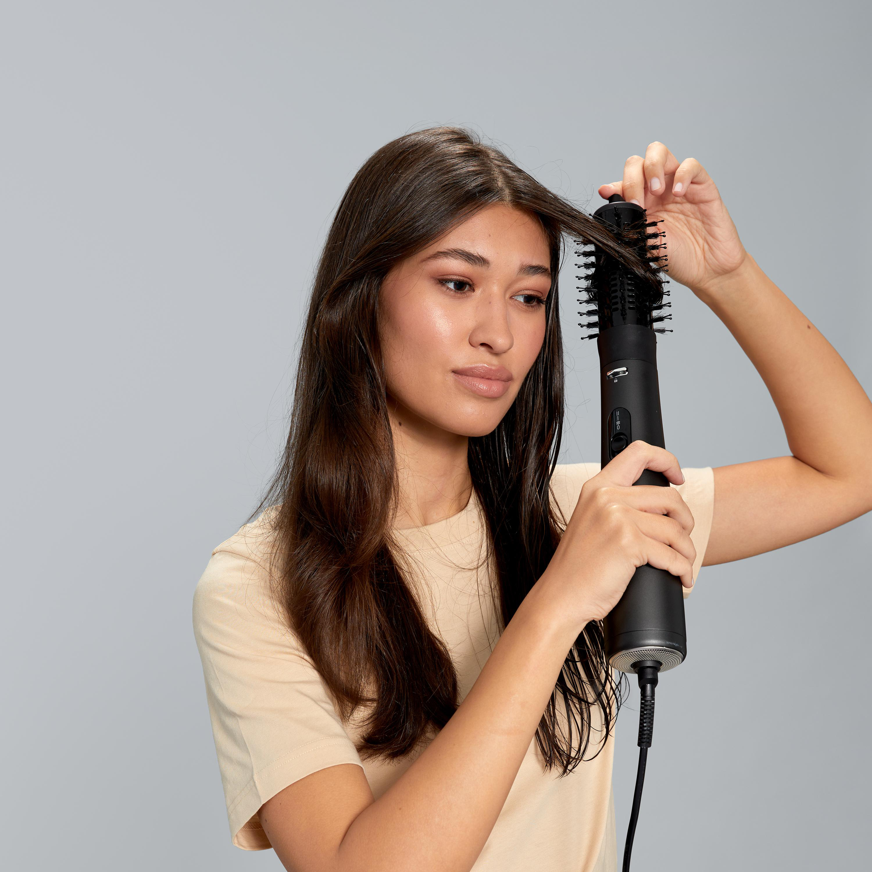 Eine Frau benutzt ein schwarzes Haarstyling-Werkzeug, um ihr Haar zu stylen.