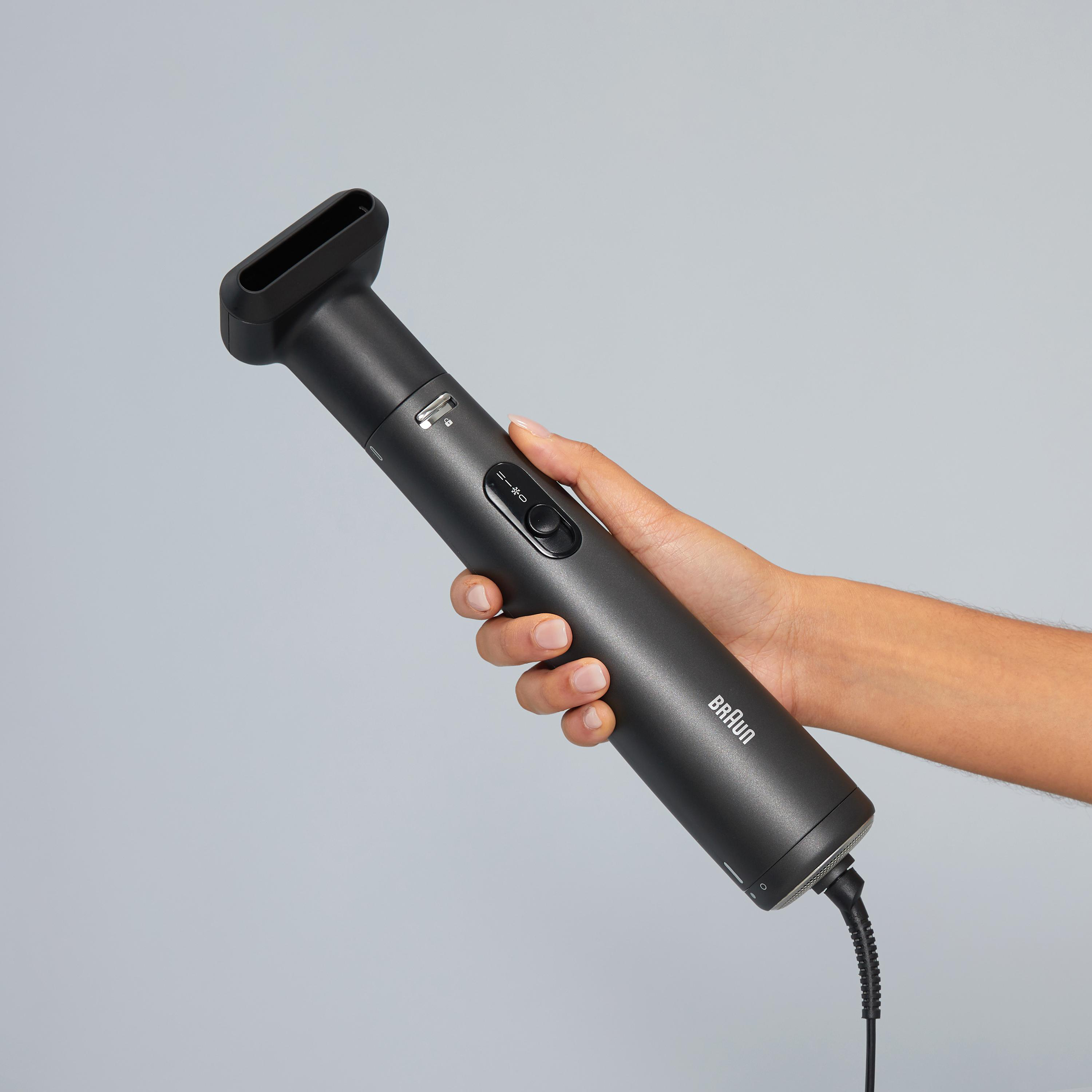 Schwarzer Haarstyler in einer Hand gehalten. Der Styler hat einen schwarzen Griff und ein quadratisches Ende.
