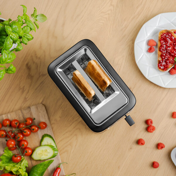 Toster z dwoma tostami, malinami, talerzem z dżemem i innymi produktami spożywczymi na stole.