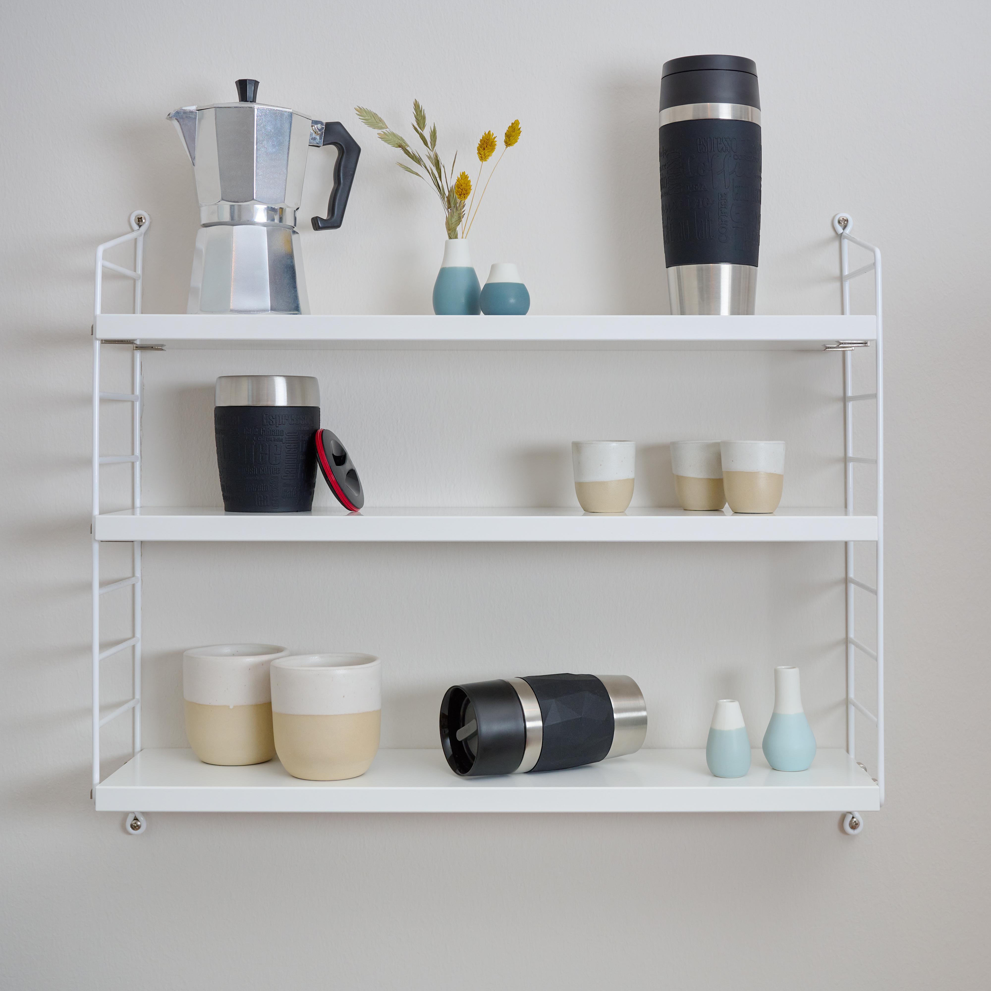 Weiße Regale mit Küchenutensilien: Kaffeemaschine, Tassen, Thermobecher und Vasen.