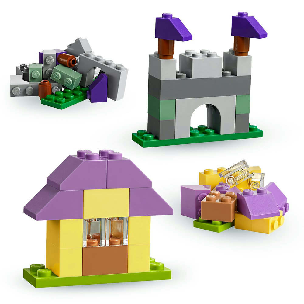 Lego-Bausteine, die zu einem Schloss, einem Haus und anderen Strukturen auf grünen Grundplatten zusammengebaut wurden.