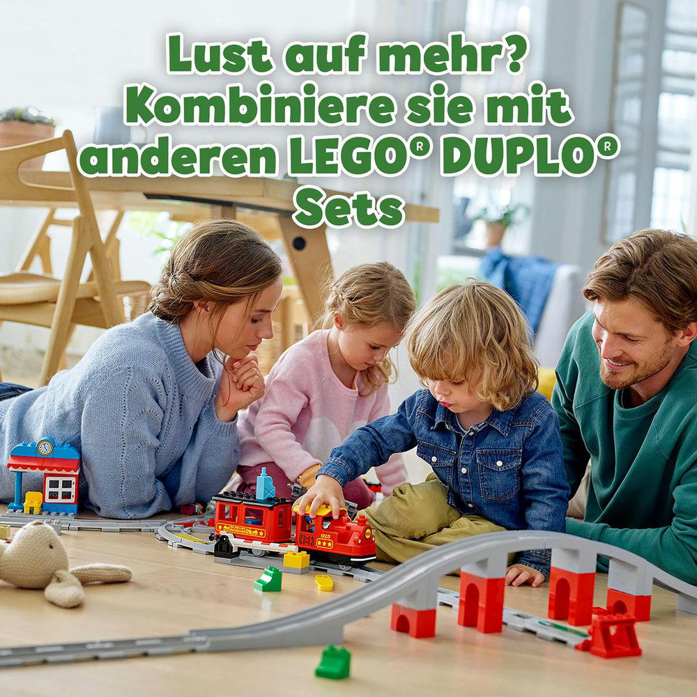 Familie spielt mit LEGO Duplo Eisenbahn. Ein Zug, eine Strecke und Figuren sind sichtbar.