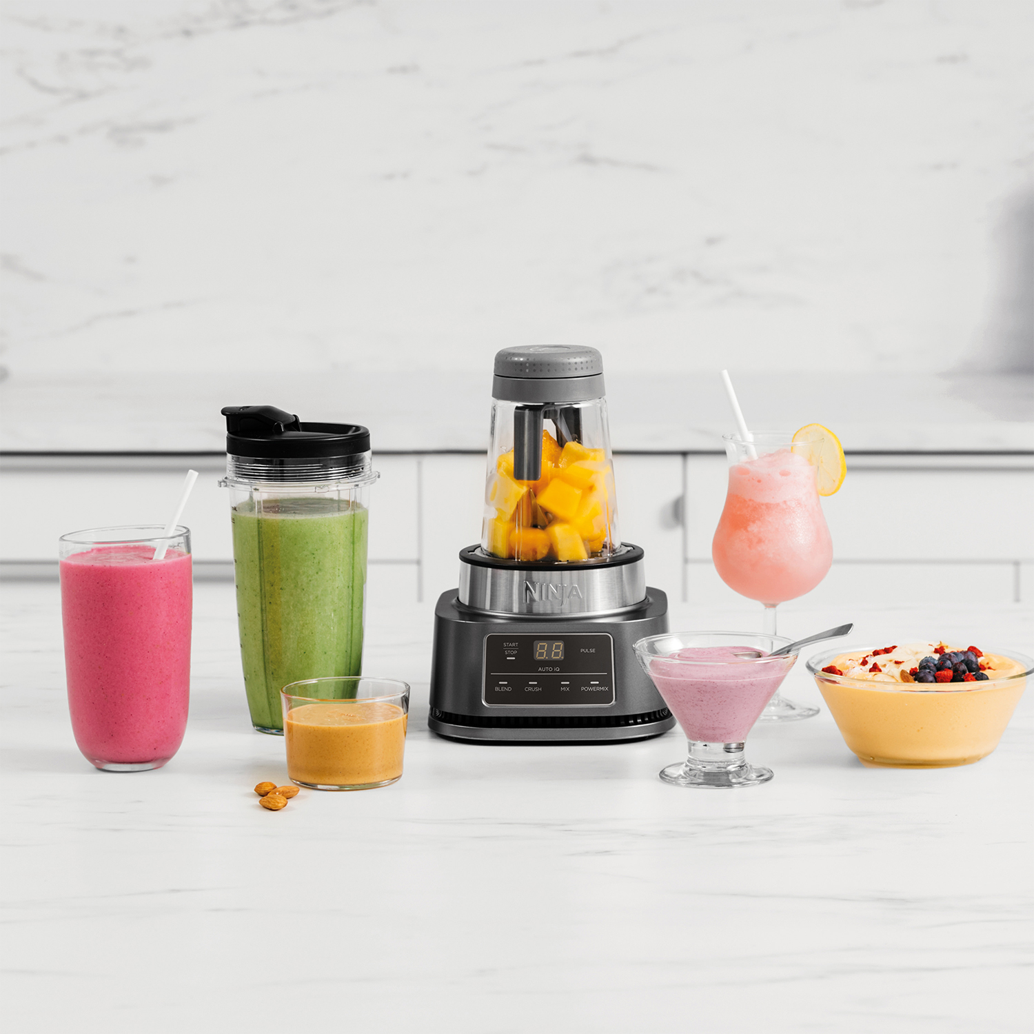 Un frullatore con frullati e ingredienti, tra cui un frullatore, frullati e uno sfondo di marmo.