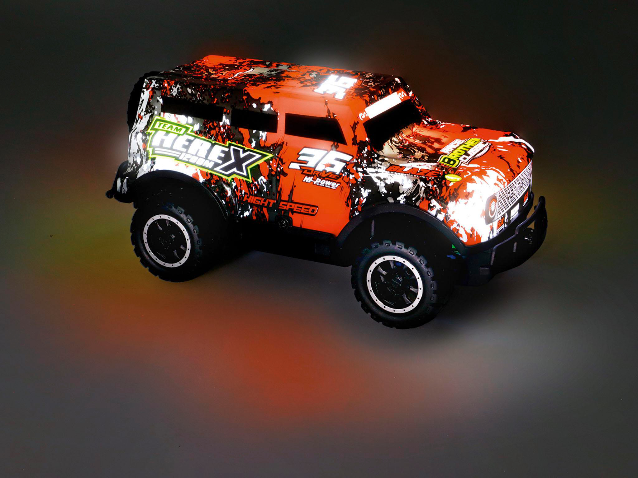 Orange-schwarzes Spielzeugauto mit Lichtern auf dunkler Oberfläche. Es hat ein robustes Design.