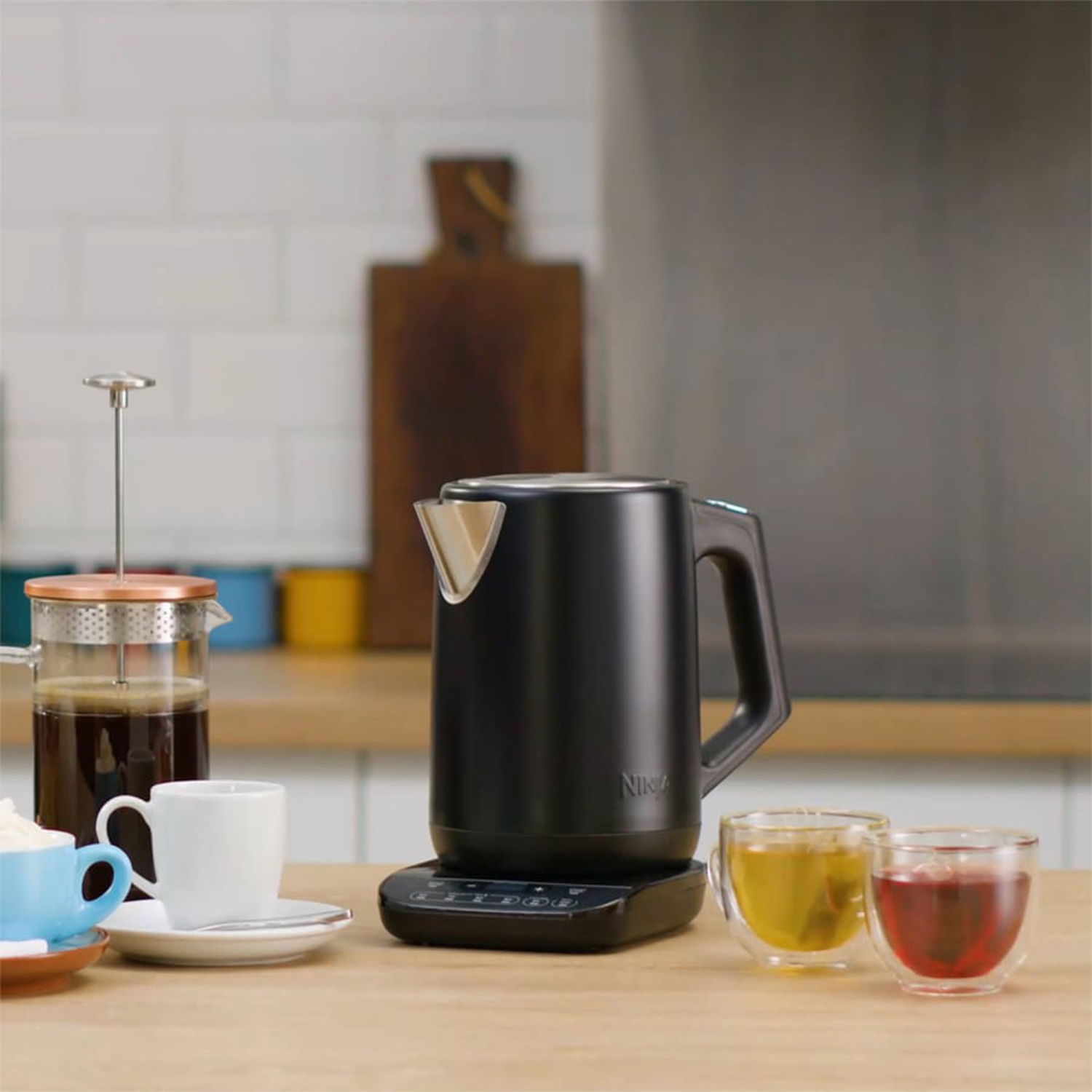 Bollitore nero con tè e caffè su un bancone della cucina.