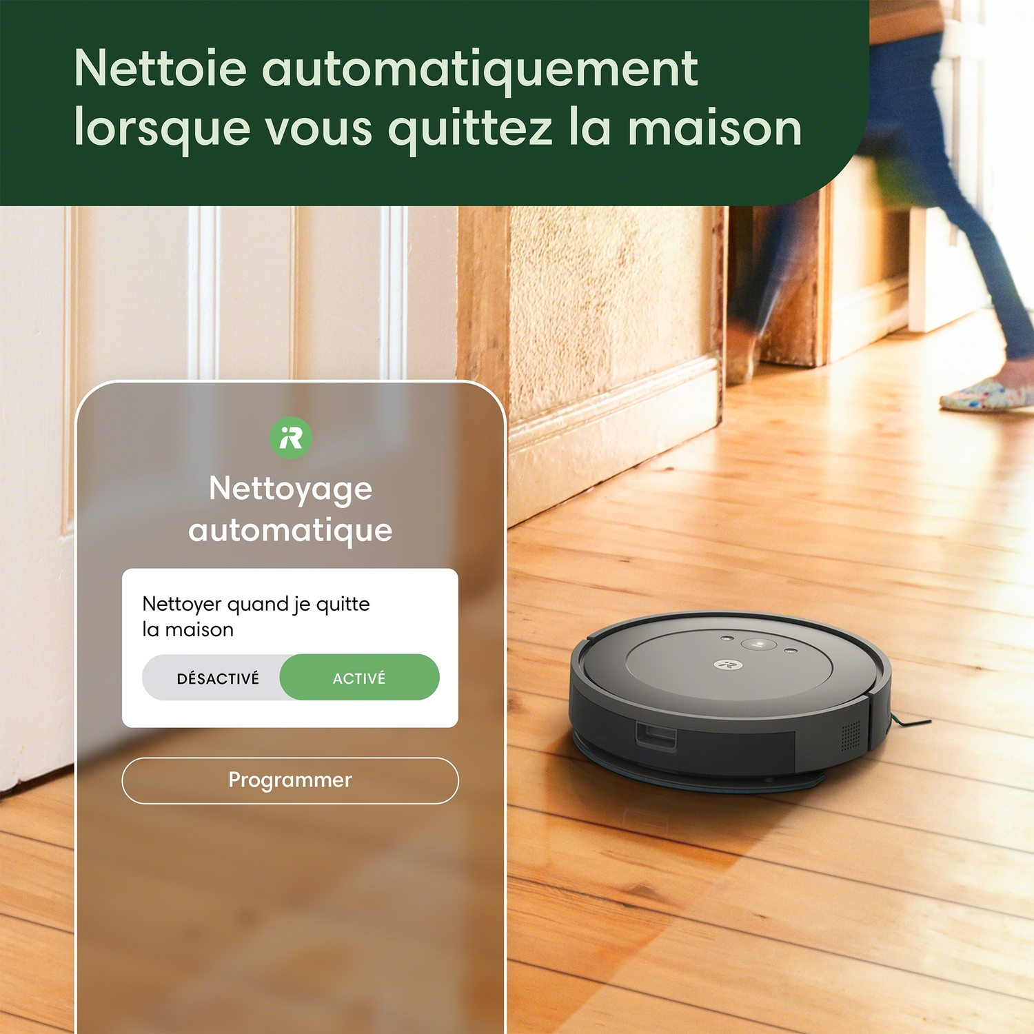 Un aspirateur robot sur un plancher en bois avec un panneau de contrôle à gauche.