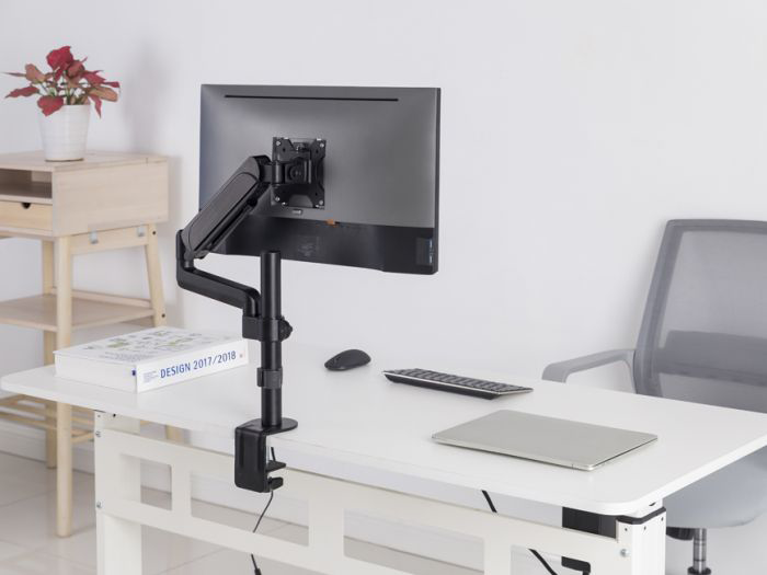 Fehér asztal, fekete monitorkarral, monitorral. Laptop, egér és billentyűzet az asztalon.