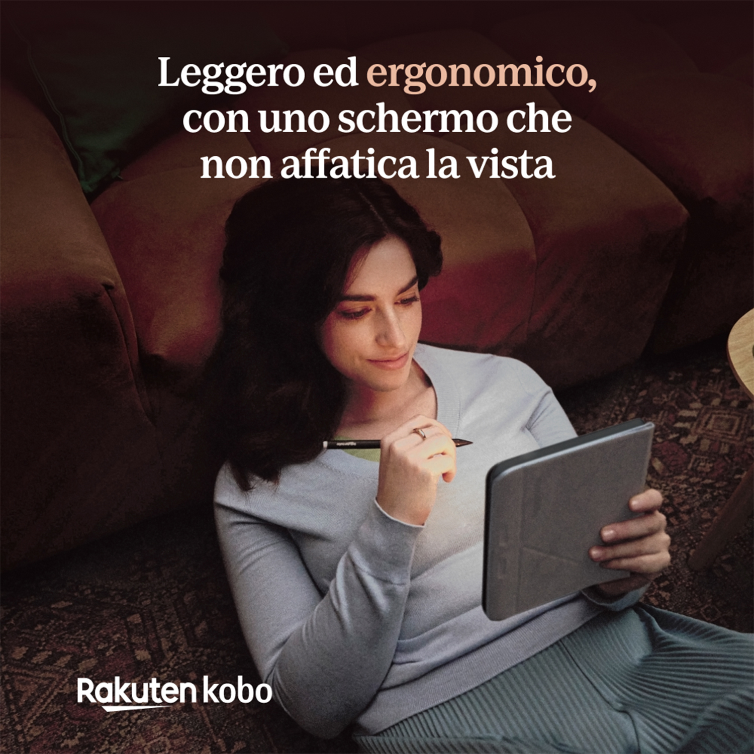 Donna che tiene in mano un tablet Rakuten Kobo. È seduta su un divano.