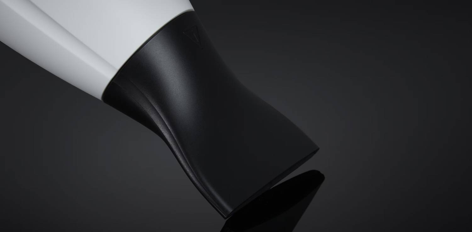 Boquilla de secador de pelo, plástico negro, primer plano sobre fondo oscuro.