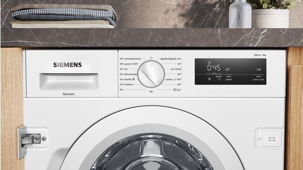 Una lavadora blanca con panel de control y cajón, con toallas encima.