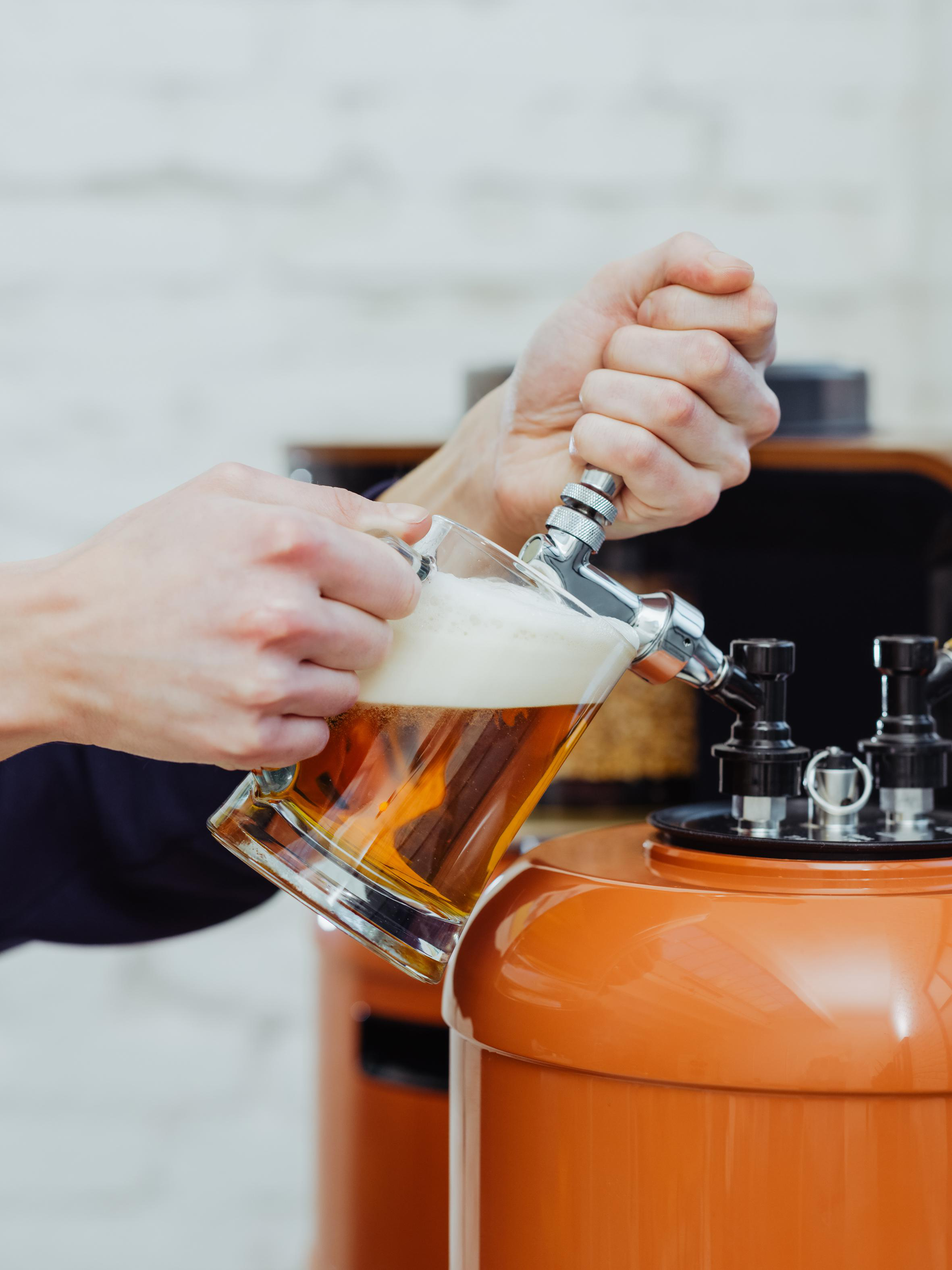 Hände, die Bier aus einem Zapfhahn in ein Glas gießen.