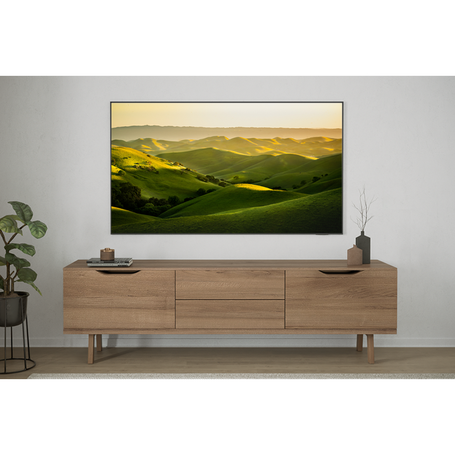 Een tv die een landschap toont boven een houten kast. Een plant en decoratie staan links.