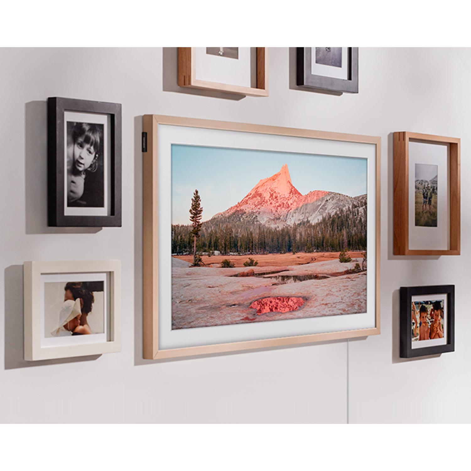 Muur met verschillende ingelijste foto's. De hoofdfoto is een berglandschap.
