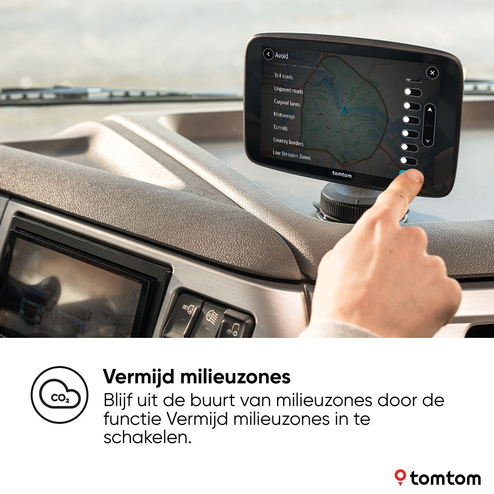 A TomTom GPS device in a car displays a map, with a finger touching its screen. The text says, avoid zones.