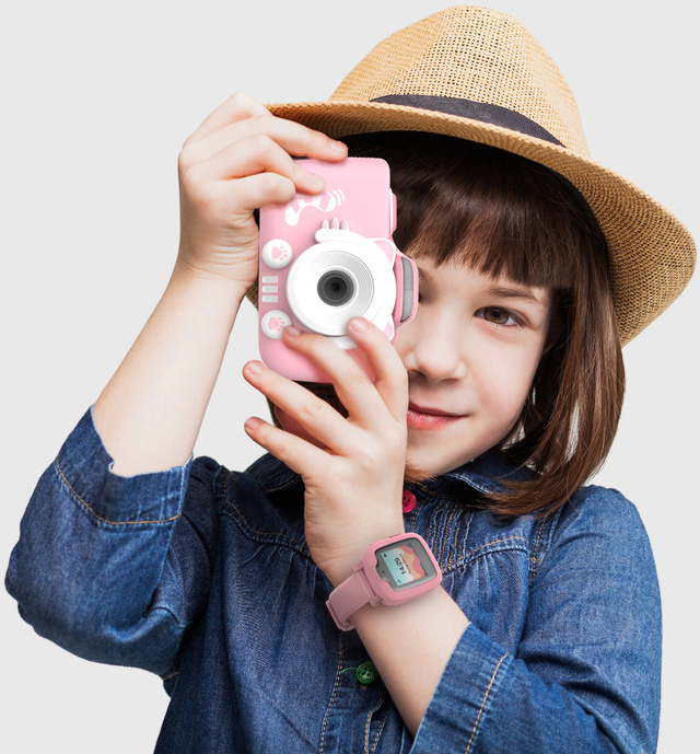 Ein Mädchen, das durch eine rosa Spielzeugkamera schaut, trägt eine rosa Uhr, mit hellem Hintergrund.