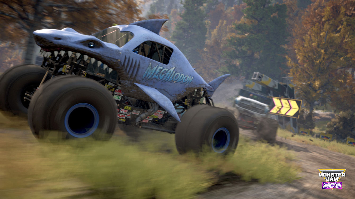 Un monster truck sur le thème du requin qui court sur une piste de terre, avec un deuxième camion en arrière-plan.