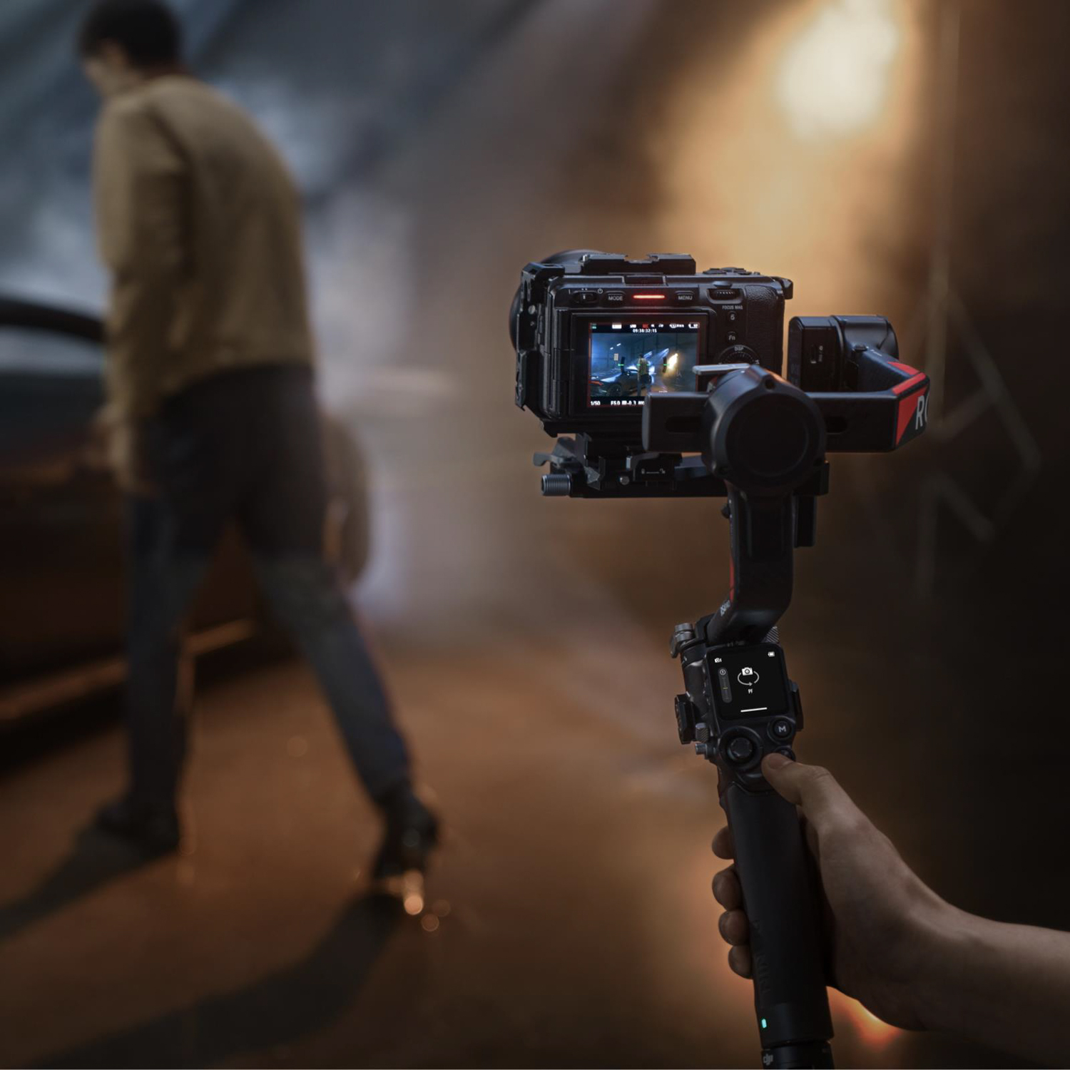 Una persona che tiene una telecamera su un gimbal, filmando una scena con sfondo sfocato.