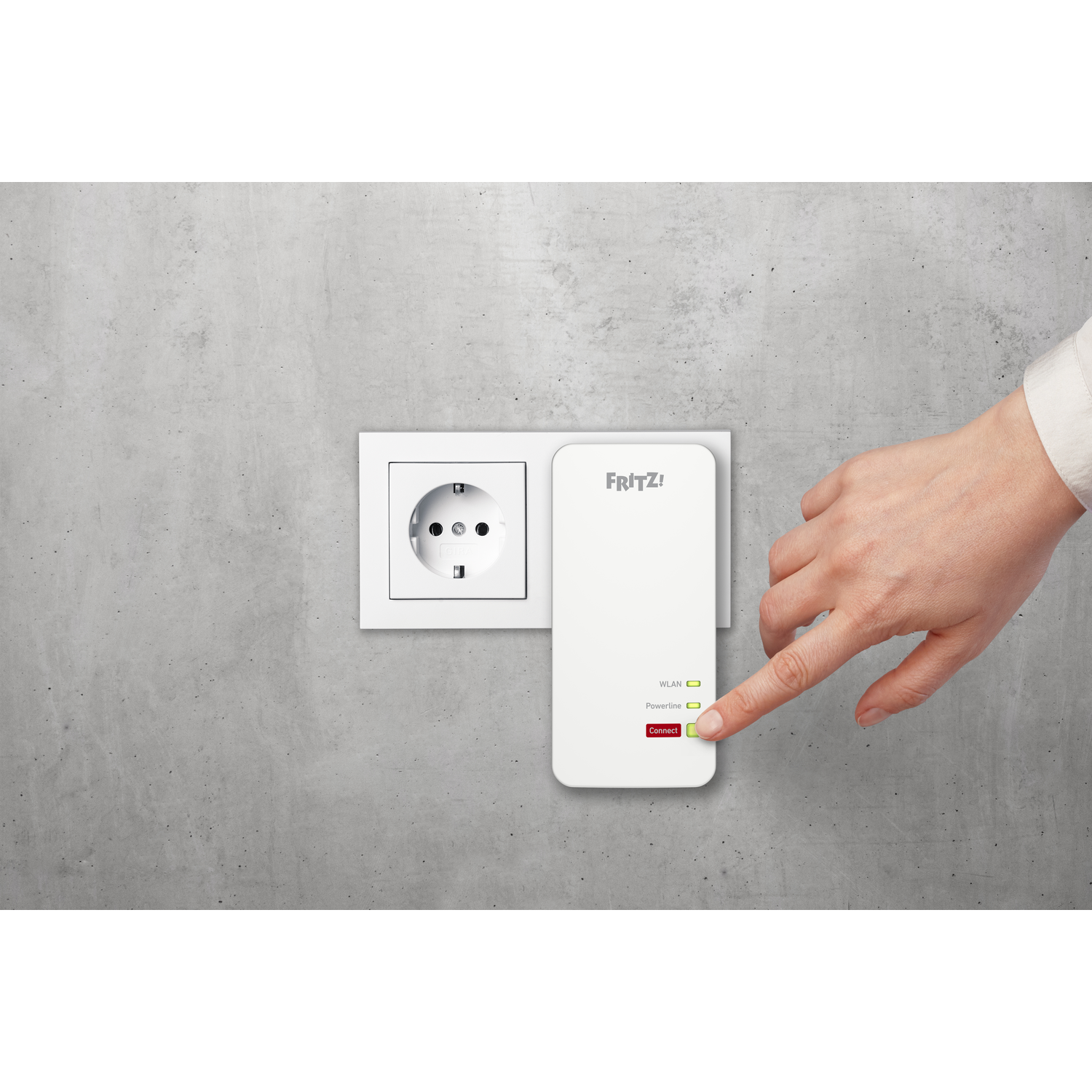 A person's hand pressing a button on a white FRITZ! repeater plugged into a wall.