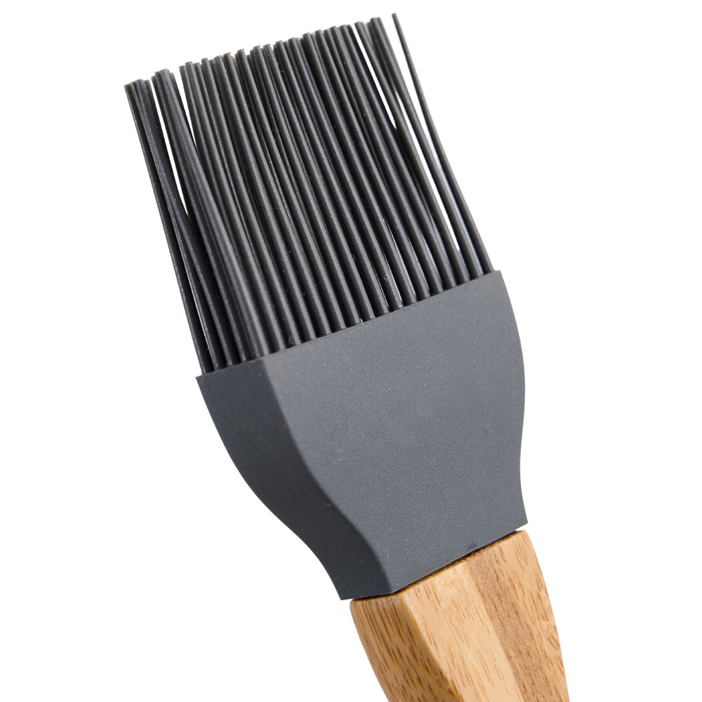 Primer plano de una brocha de silicona gris con mango de madera.