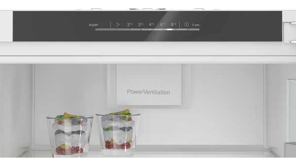 Interior de un refrigerador con panel de control y dos postres en vasos.