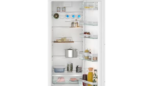 Interior de refrigerador lleno de alimentos en estantes y cajones.